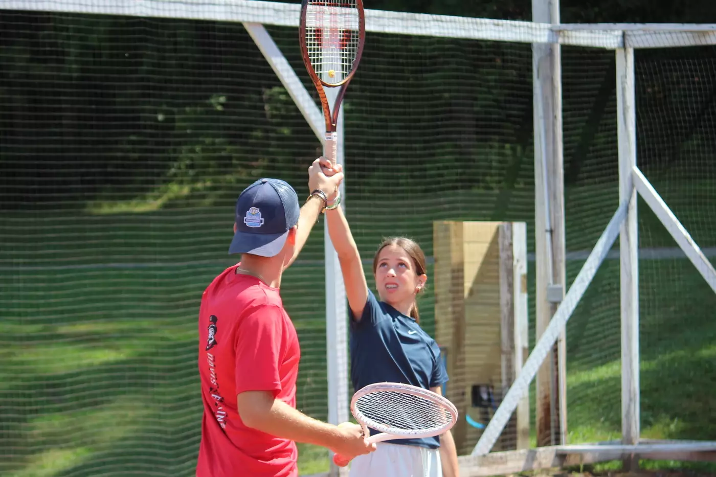 A coach works with a camper during a private tennis lesson