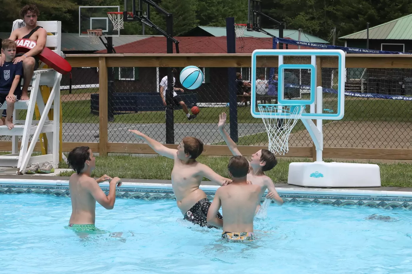Windridge campers enjoying the poolside basketball hoop during the swimming elective.