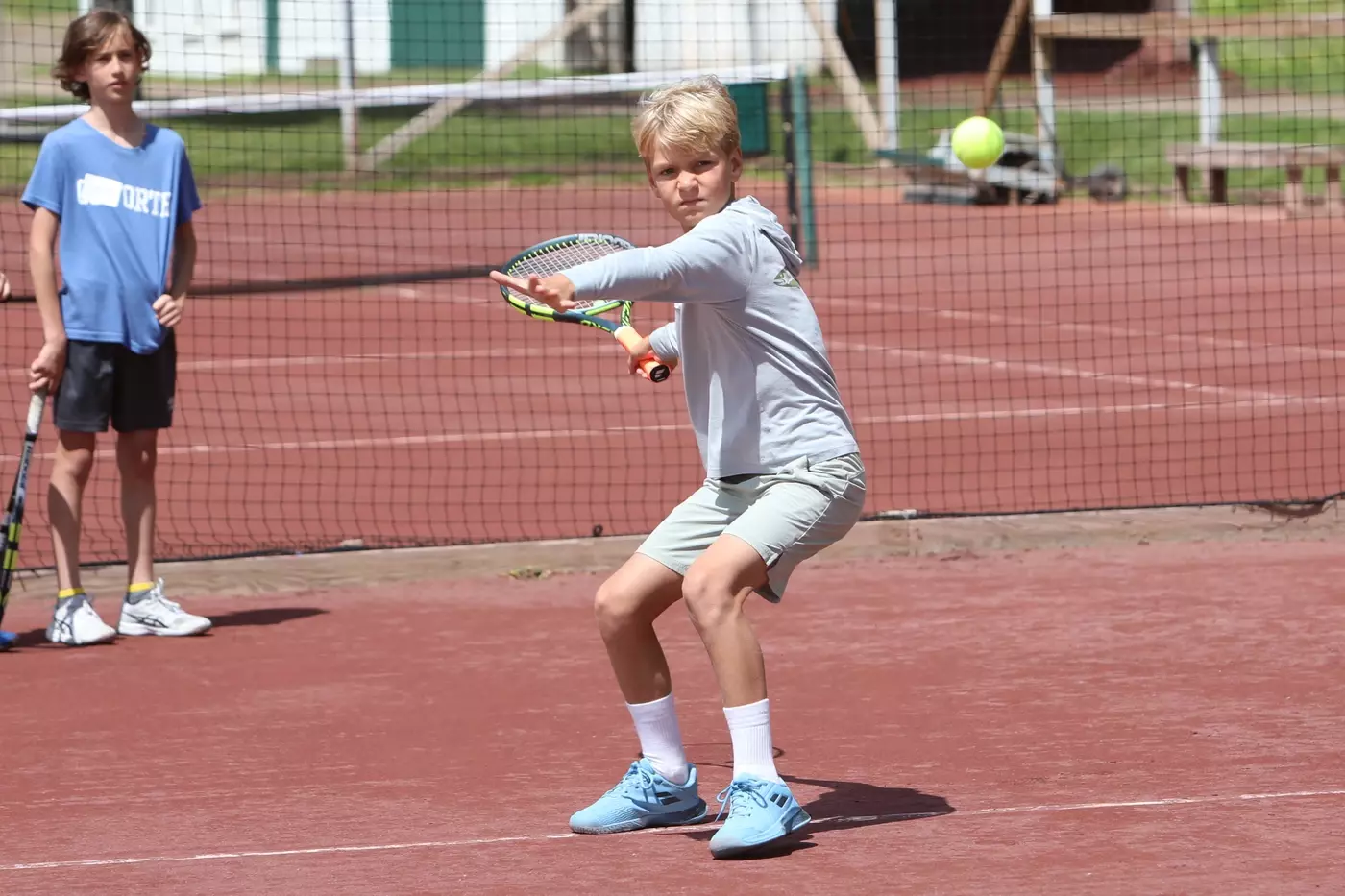 A Windridge camper hits a forehand on the red clay courts