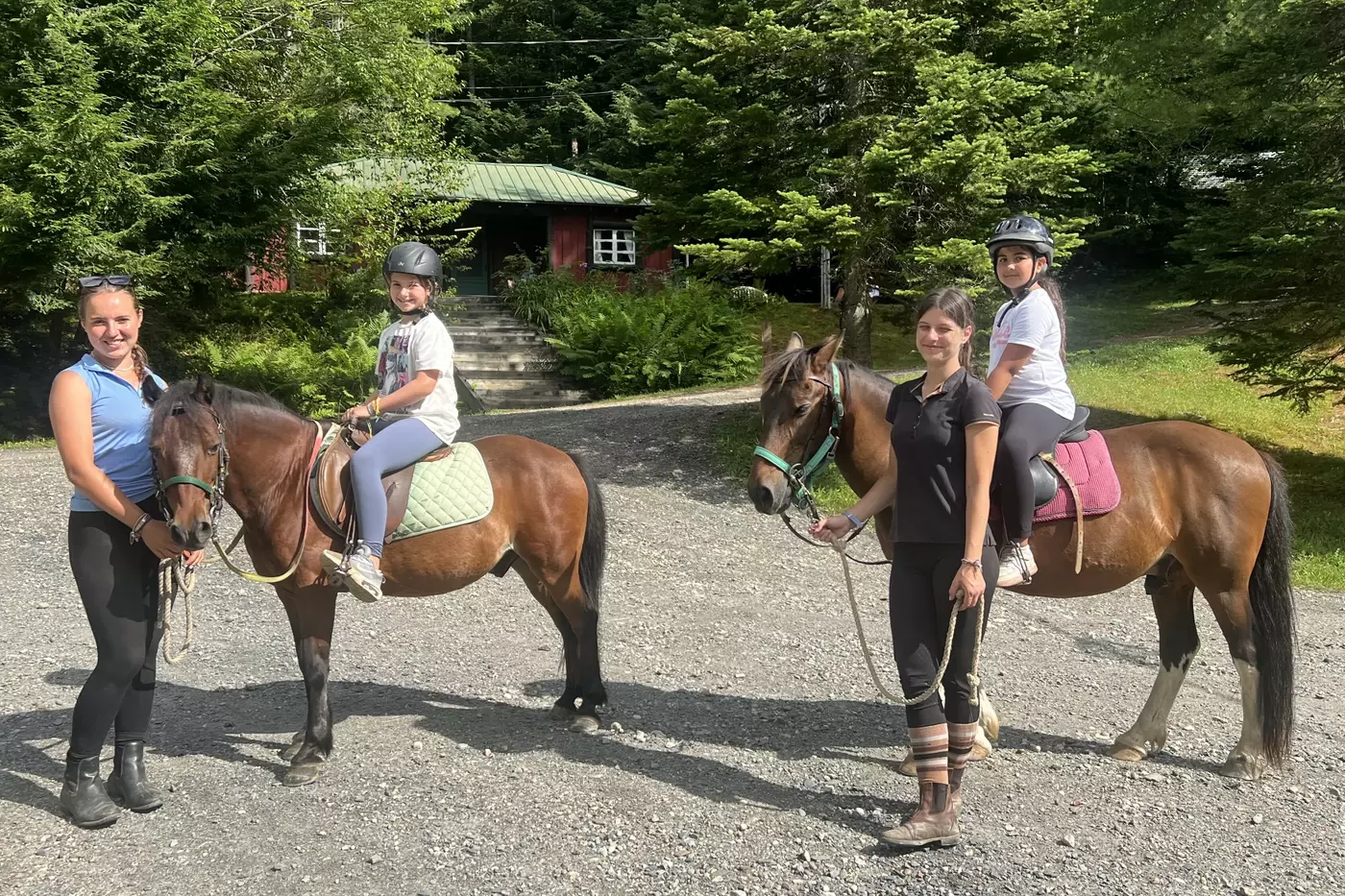 Two Windridge campers riding horses around camp.