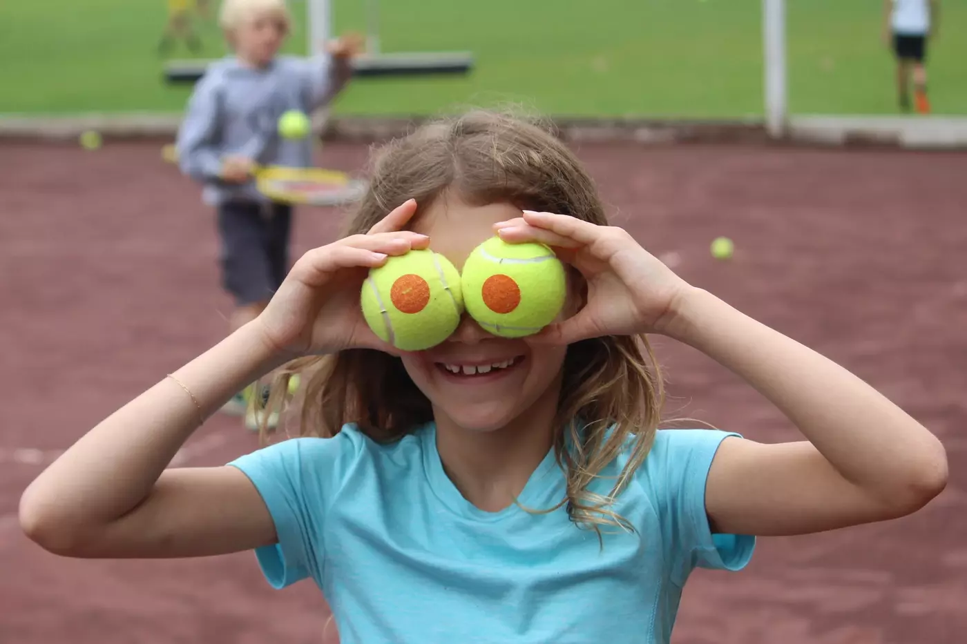A Windridge camper holds up tennis balls in front of her eyes