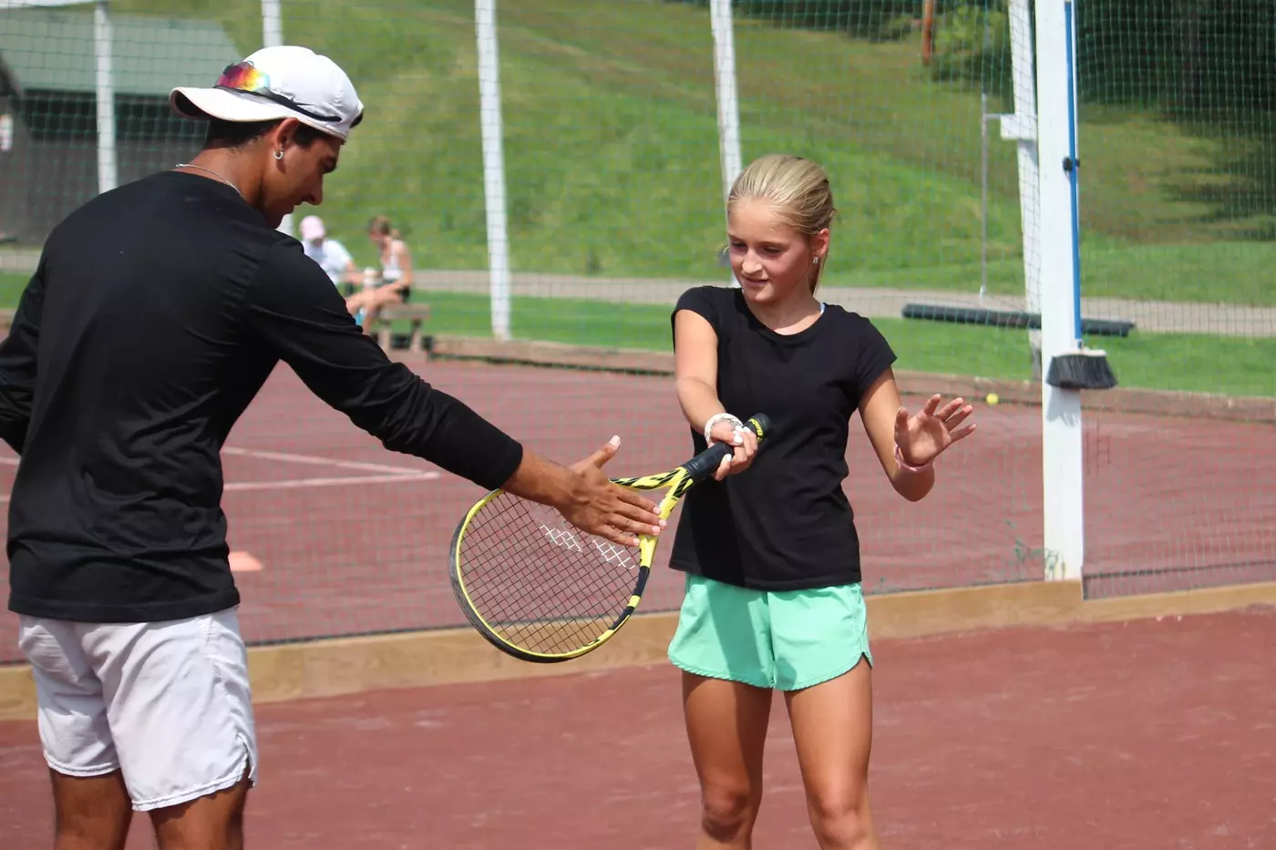 A Windridge tennis counselor works with a camper.