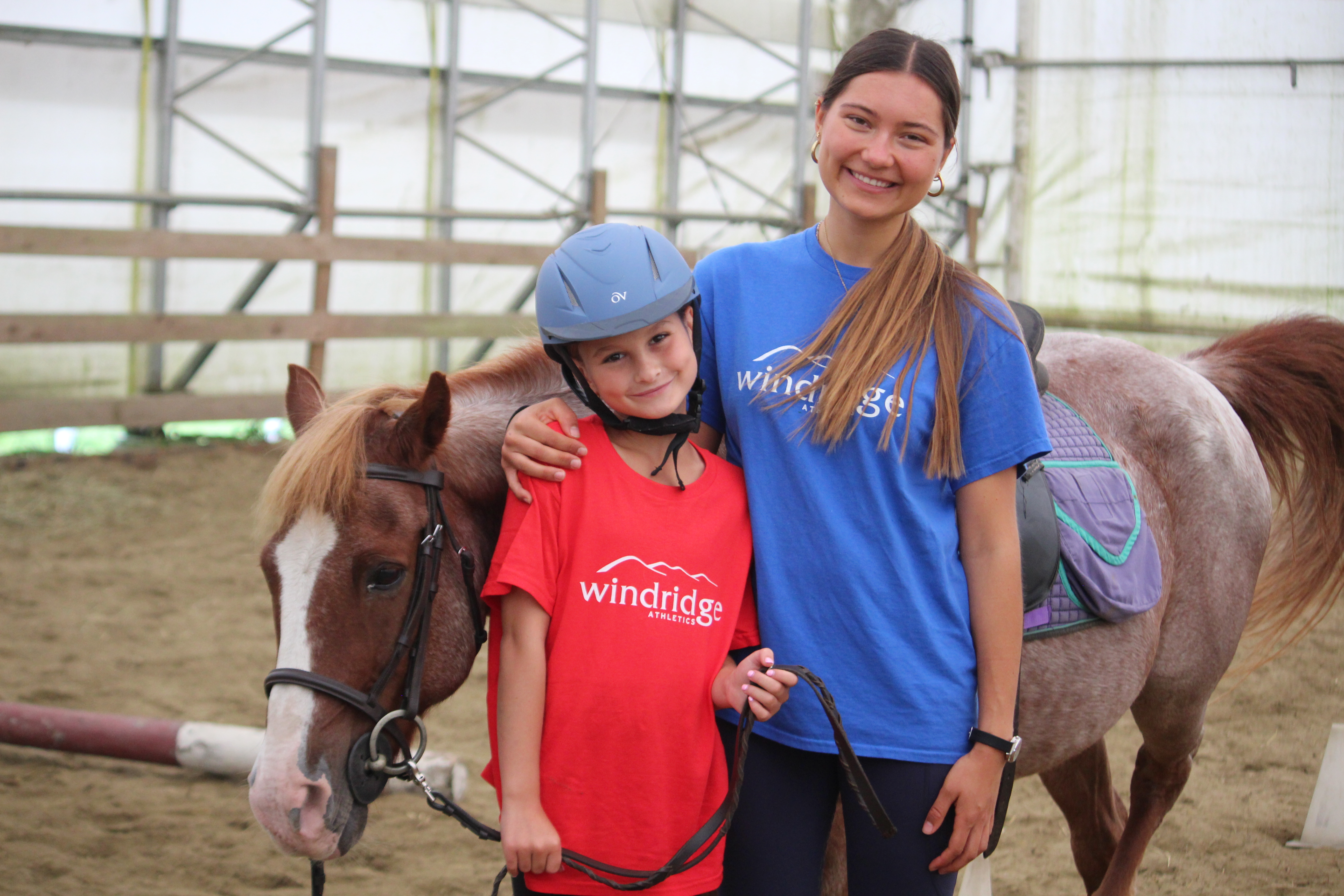 A Windridge Riding counselor with a horse and camper